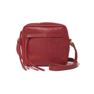 A red crossbody camera bag handcrafted from sustainable leather and upcycled brass hardware, featuring a hand-loomed cotton lining and an interior pocket.