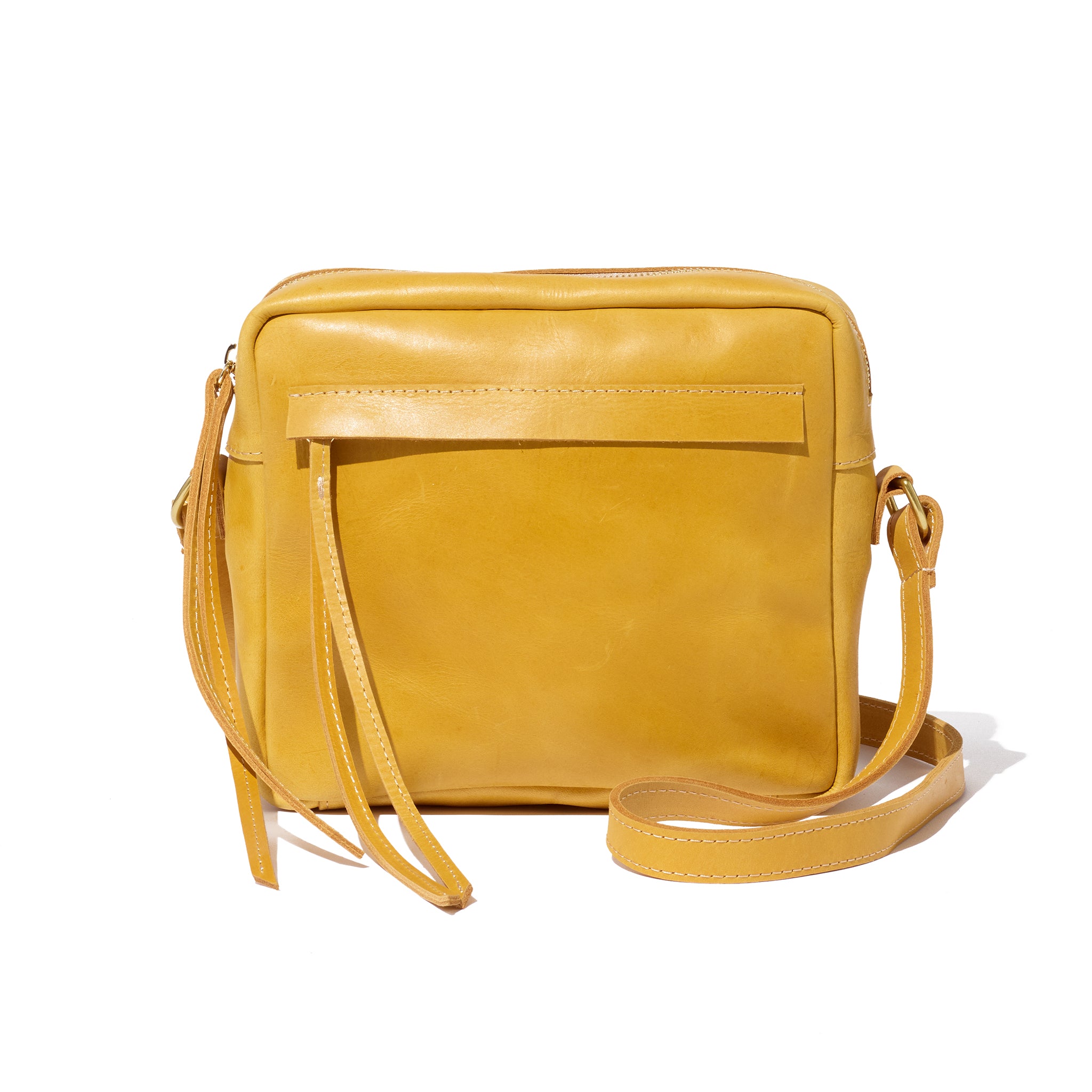 A yellow crossbody camera bag handcrafted from sustainable leather and upcycled brass hardware, featuring a hand-loomed cotton lining and an interior pocket.