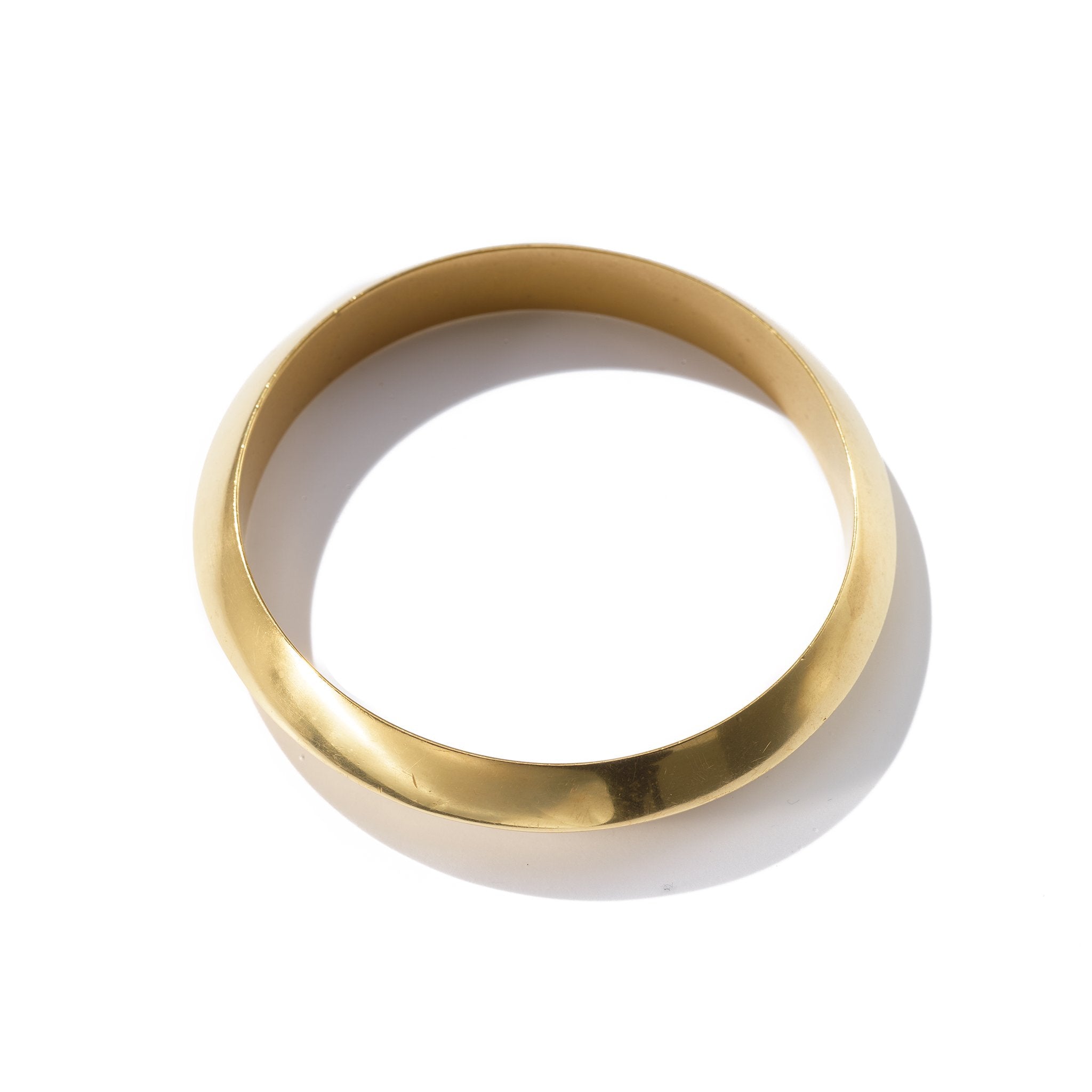 A classic bangle with a sculpted knife edge handcrafted from upcycled brass.