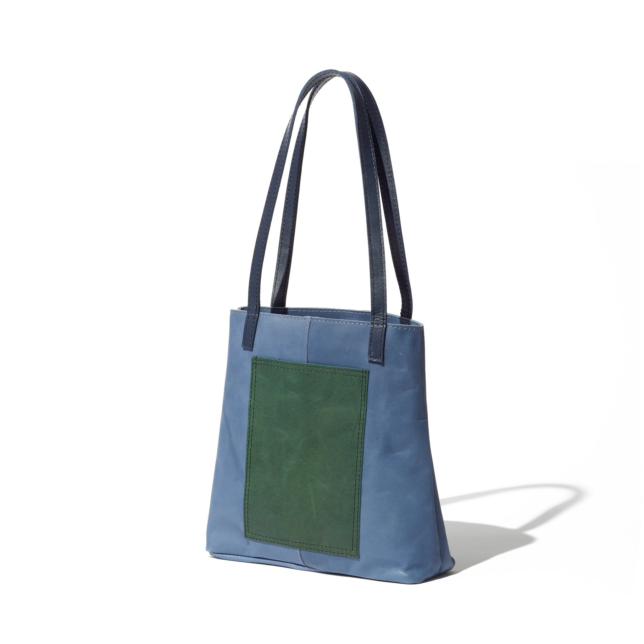 Just the right size for everyday, this blue and green tote is handcrafted from sustainable leather and features an exterior pocket.